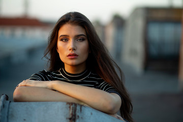 Obraz premium Young woman with green eyes, posing sensually on the roof, her hair is in wind at sunset. Black and white picture.