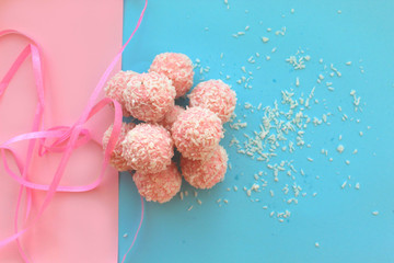 Pink candies on a blue and pink background stacked with a ribbon, reminiscent of Raffaello