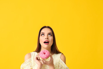 Beautiful young woman with donut on color background