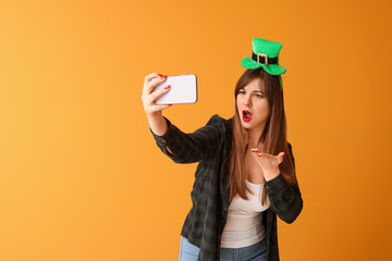 Funny young woman taking selfie on color background. St. Patrick's Day celebration