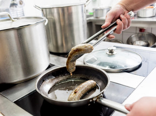 Cooking sausages in a pan. Grilled sausage in a skillet. Restaurant.
