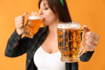 Funny young woman with beer on color background. St. Patrick's Day celebration