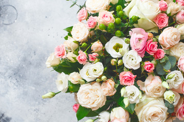 Bouquet of beautiful flowers with peonies, roses and eustomas in the papper gift box in front of grey grunge background. Closeup picture. Valentine's Day. Mothers Day