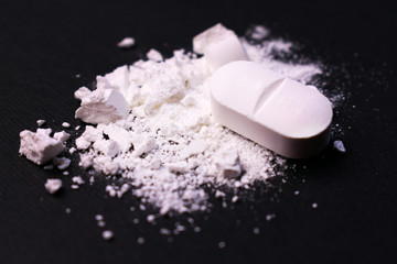  Crushed pill on a black background. Close-up. Drug abuse.