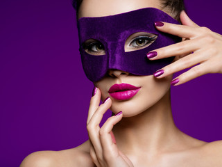 Portrait of a beautiful  woman with purple nails and violet theatre mask on face.