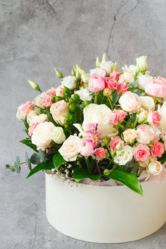 Bouquet of beautiful flowers with peonies, roses and eustomas in the papper gift box in front of grey grunge background. Closeup picture. Valentine's Day. Mothers Day