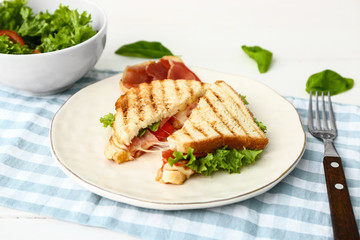 Plate with tasty sandwiches and vegetable salad on table
