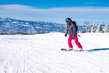 Active young snowboarder riding snowboard down the hill with beautiful winter landscapes in the...