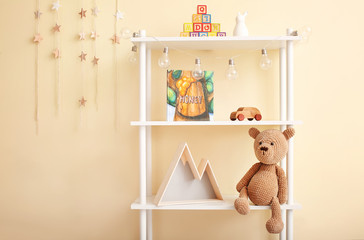 Shelf with baby toys, book and decor near color wall