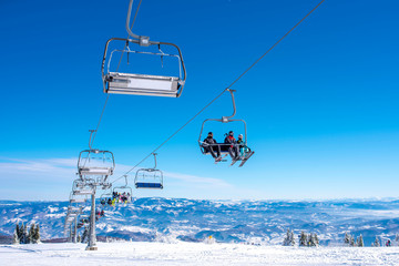 People on ski lift at mountain ski resort with beautiful sky and mountains in the background