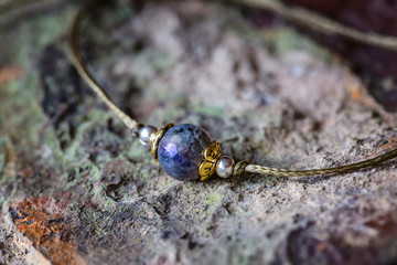 Labradorite fazeted gemstone tiny bracelet on rocky background