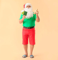 Santa Claus with passport, tickets and toy airplane on color background. Concept of vacation