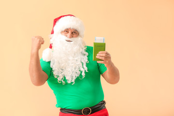 Fototapeta na wymiar Santa Claus with passport and tickets on color background. Concept of vacation