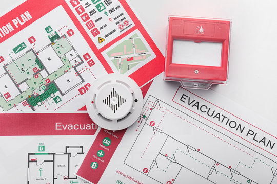 Evacuation plans, smoke detector and manual call point on white background