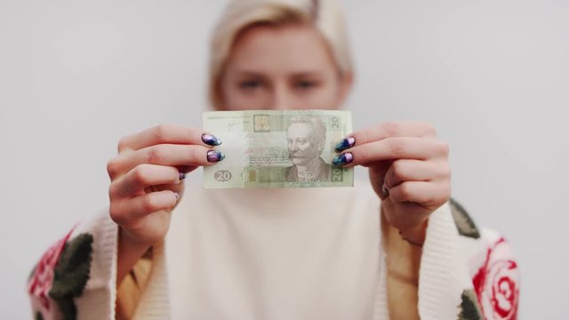 twenty Hryvnia (Hrivna, Grivna, Hrivnia) Banknote in the hands of the beautiful blond woman. Selective soft focus close up studio slow motion shot