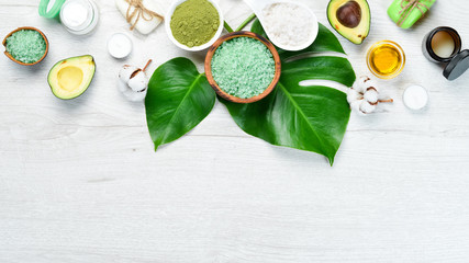Cosmetics from avocado, avocado oil, sea salt and face cream, on a white wooden background. The concept of cosmetics and spa. Top view. Free copy space.