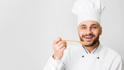 Chef Guy Tasting Dish Holding Spoon Posing On Gray Background