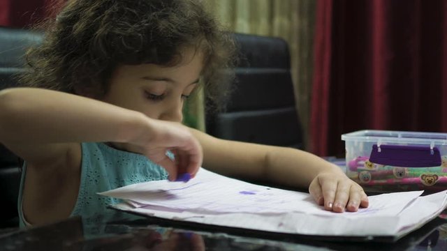 Young child sitting at a table coloring drawing a picture on a sheet of paper