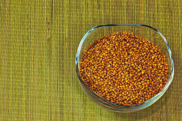buckwheat groats in a glass cup standing on a straw mat