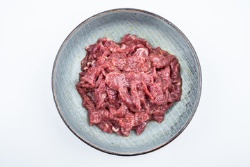 Fresh marinated beef slices on a plate on white background