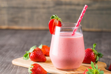 Glass of fresh strawberry milkshake, smoothie and fresh strawberries on pink, white and wooden...