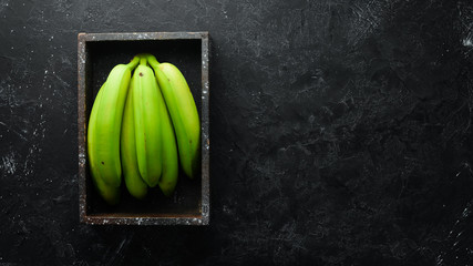 Fresh green bananas on black stone background. Top view. Free space for your text. © Yaruniv-Studio