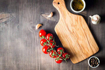 Wooden Cutting Board with Fresh Herbs and Raw Vegetables on Rustic Wood Table. Top view. Cooking background.