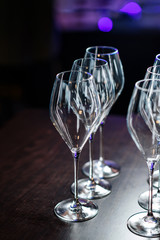 Desert wine glasses on the bar counter. Reflected in glass, neon lights.