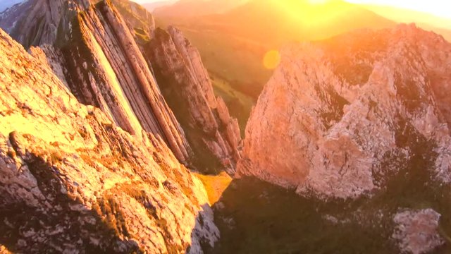 Slow motion FPV drone shot, around a man standing on the Alpstein ridge, in the Appenzell Alps, at sunset, on a sunny summer evening, in Switzerland