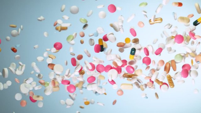 Super slow motion of falling mixed pills on blue background. Filmed on high speed cinema slow motion camera, 1000fps.