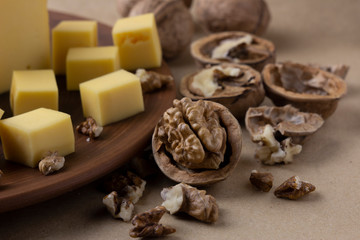 Close-up on a big walnut. Cheese lies on a plate next to it. The concept of proper nutrition