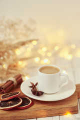 Cozy autumn or winter concept. Cup of coffee with a garland lights and decoration/