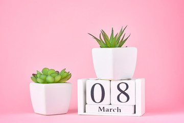 Women's Day concept. Wooden calendar block with date 8 march and plant on the pink background with copy space