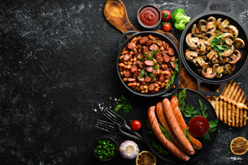 Set of dishes of meat and vegetables on black background. Top view. Free space for your text.