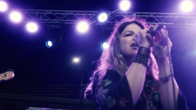 Close up in slow motion of Female rock singer, singing a song in an outdoor concert