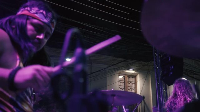 Camera moving from left to right side on the right side of a drummer playing a song in an outdoor concert