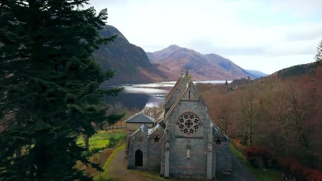 Slow flight toward church on loch in Scotland and pass by steeples