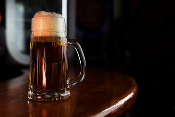 Beer in a Mug with Foam Resting on a Wooden Surface with Blank Space for a Logo or Text