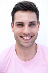 Fototapeta premium Close up handsome young man smiling by white wall