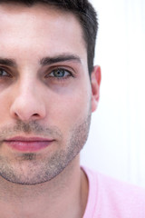 Cropped face portrait of male fashion model by white background