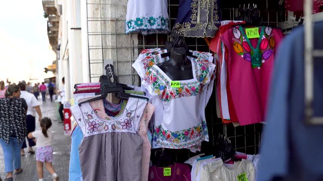 Camera pans down showing shop selling Mexican blouses for women in Merida.