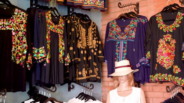 Camera pans left showing black and colorful huipil blouses in Merida, Mexico.