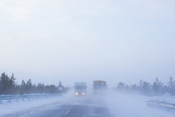 cars go on a winter road with poor visibility, weather and snowstorm