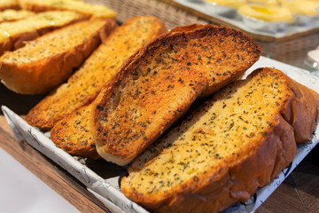 freshly baked delicious garlic bread with herbs, sliced, on the window counter of a bakery store, close-up photo