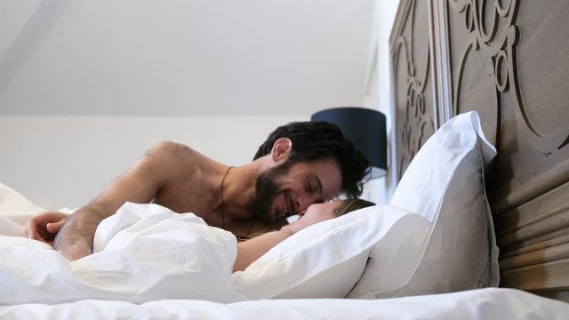young couple inlove waking up in bed together. Romantic morning kisses and hugs. 4K