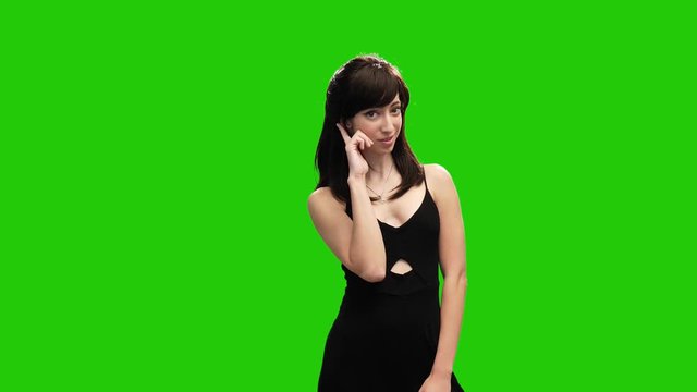 Petite woman posing on green screen pointing finger towards camera and surprised