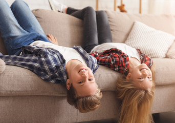 Brother And Sister Sitting On Couch Upside Down At Home