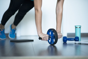 Abdominal roller or roll wheel used by female at gym