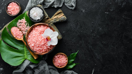 Pink fragrant sea salt in a bowl. On a black stone background. Spa treatments. Top view. Free space for your text.