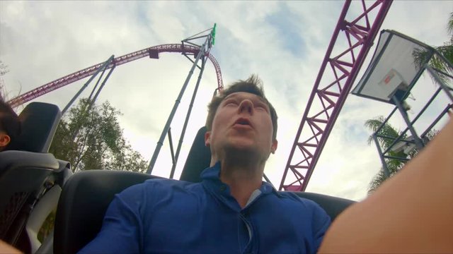 Inside high-speed rollercoaster, on-ride flash camera taking photo of thrilled young man